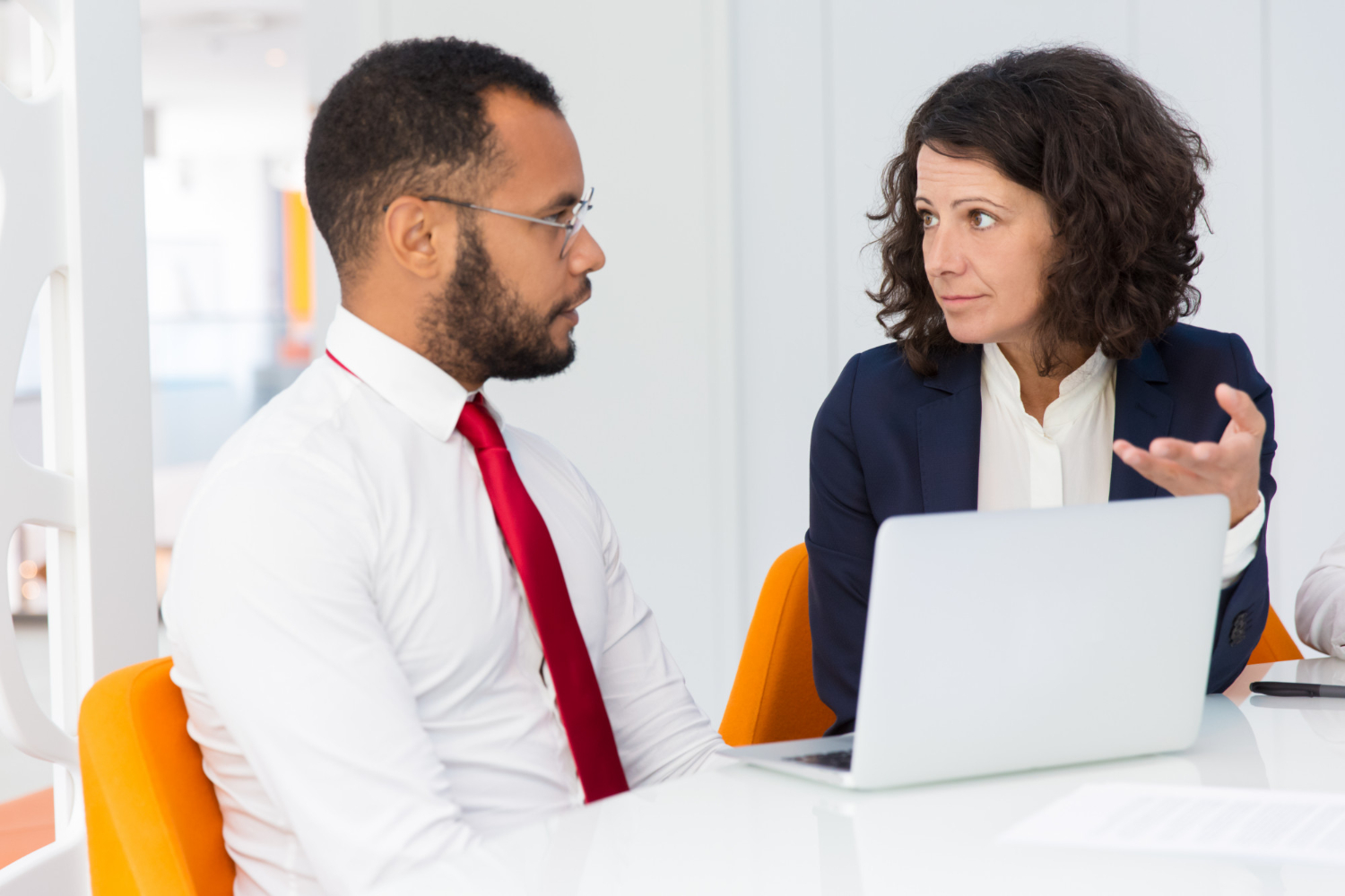 Técnicas efectivas de prospección comercial 1 Dos profesionales en una reunión de negocios, discutiendo estrategias de prospección comercial con un portátil entre ellos.