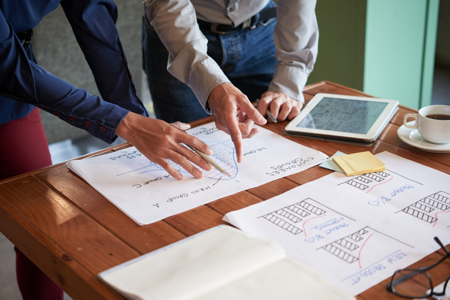 Técnicas efectivas de prospección comercial 3 Manos de profesionales señalando técnicas efectivas de prospección sobre una mesa de trabajo, con gráficos y una tablet a un lado.